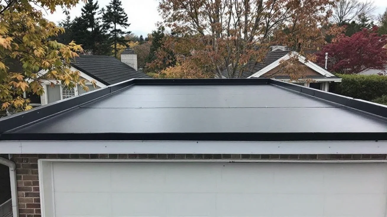 Flat garage roof covered in a smooth black rubber membrane with a metal drip edge